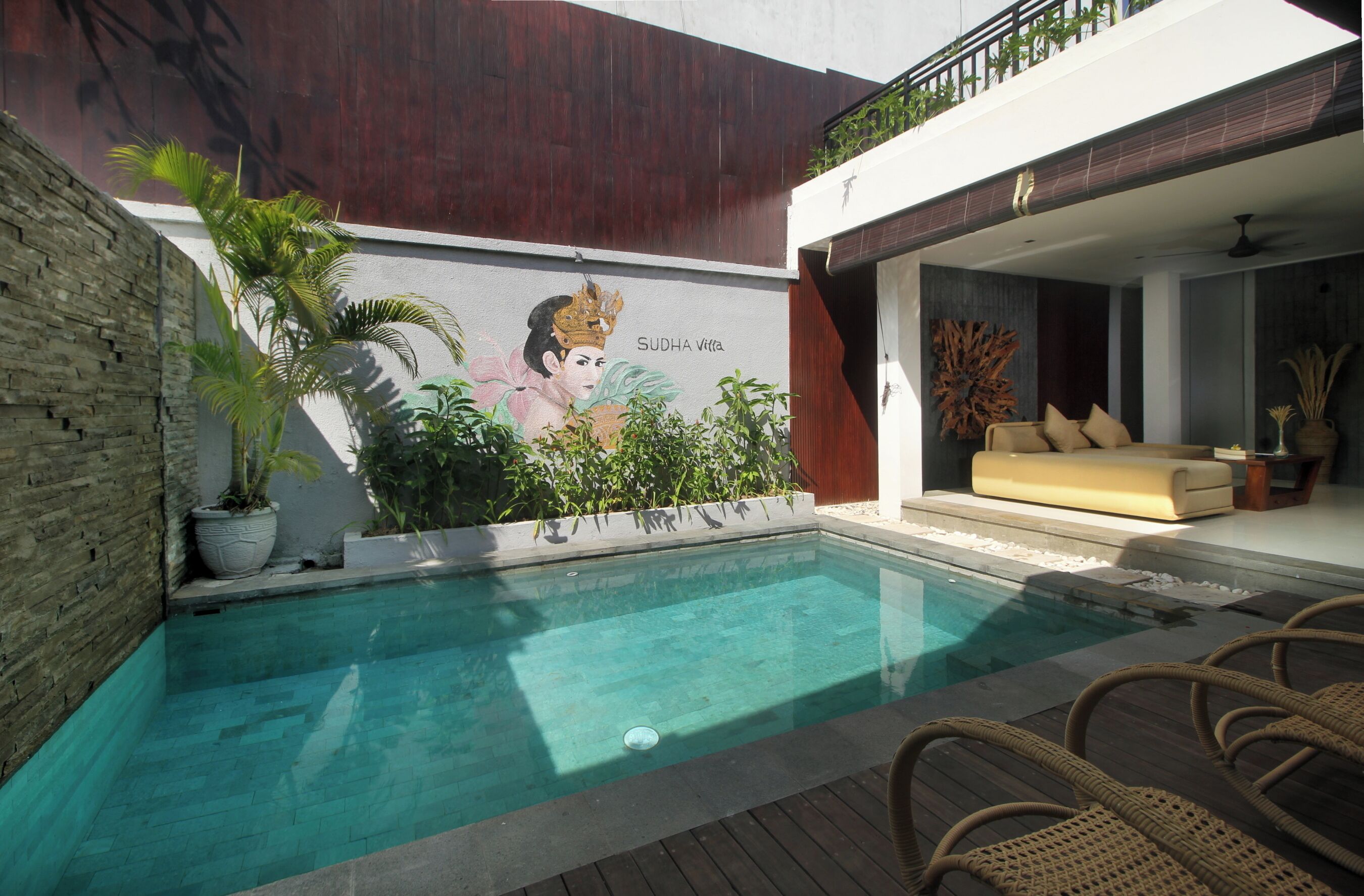 A swimming pool with a mural, a wooden deck, and a lounge area with a sofa.