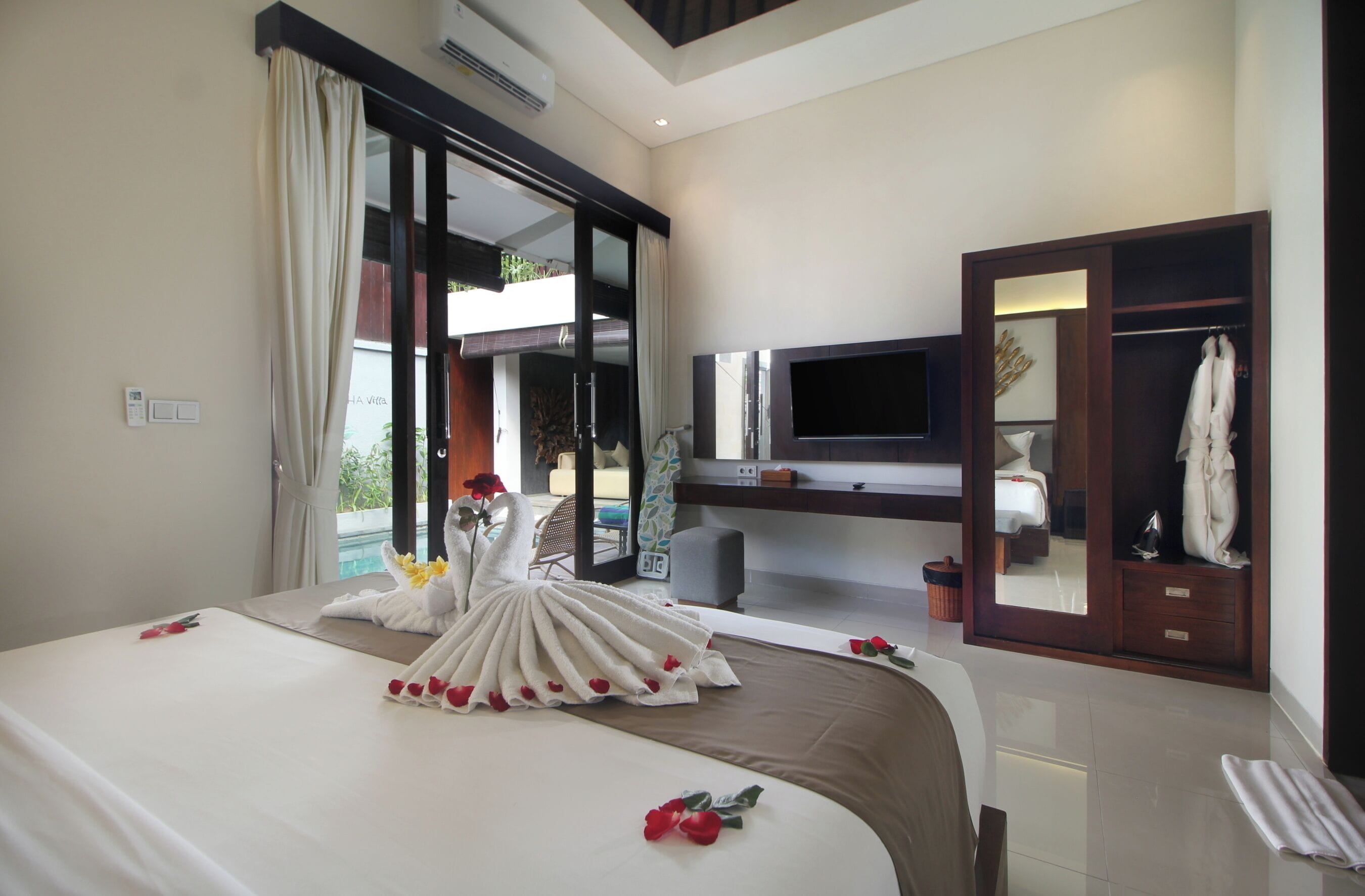 A hotel room with a bed, a TV, a wardrobe, and a balcony.