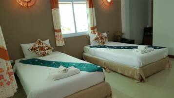 Habitación de hotel con dos camas, una ventana con cortinas, una lámpara de noche y un aplique de pared.