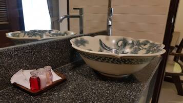 Un baño con encimera de granito, un lavamanos grande con un diseño decorativo y un espejo que refleja el lavamanos y la ventana.