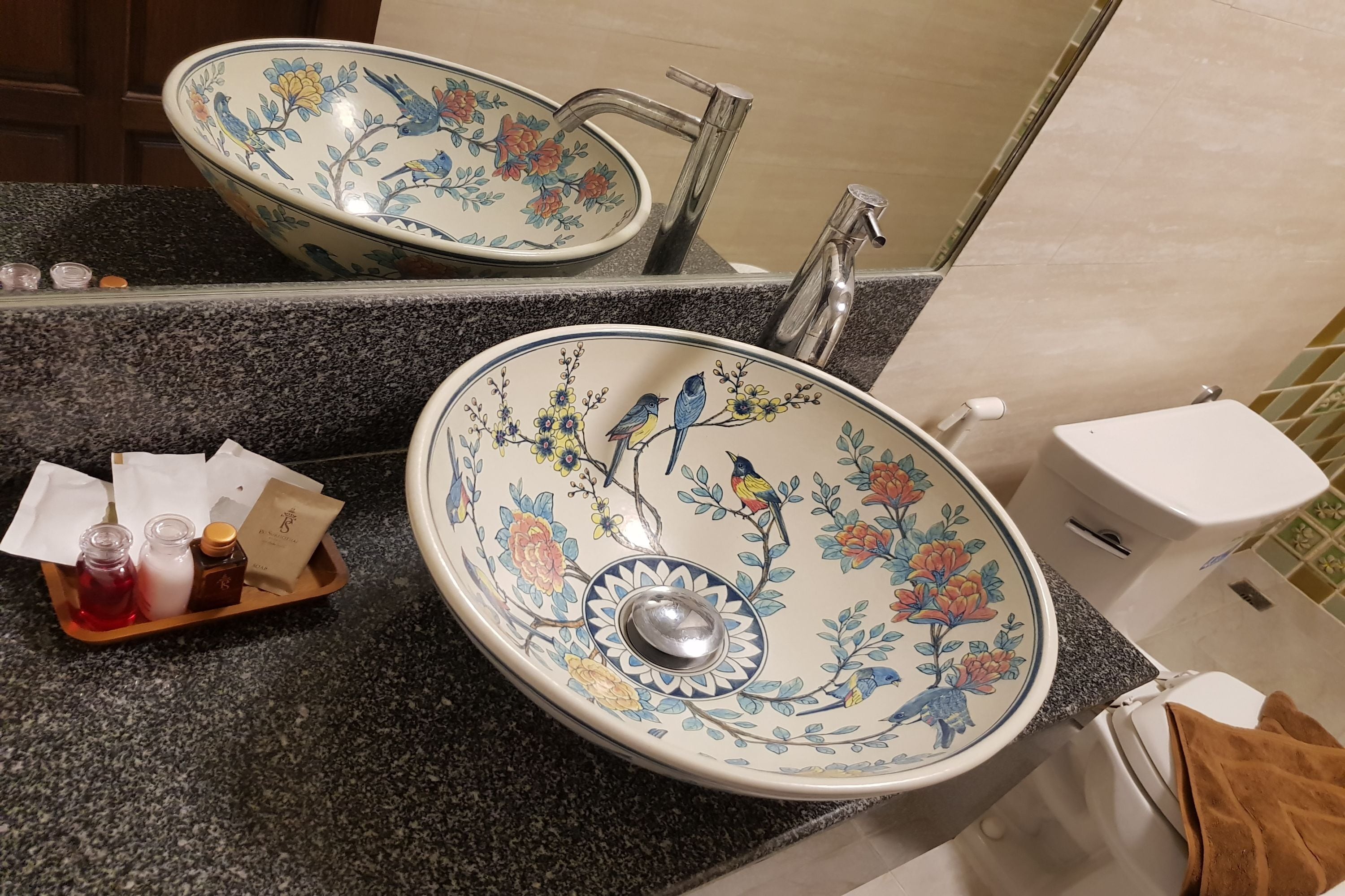 A bathroom with a double sink, a mirror, and a toilet.