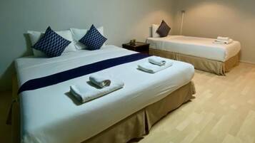 Una habitación de hotel con una cama grande, una cama más pequeña y una mesita de noche.