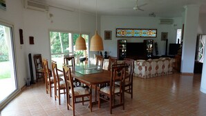 A spacious living room with a dining area, large windows, and a ceiling fan. - Hilltop Boosa (Boossa)