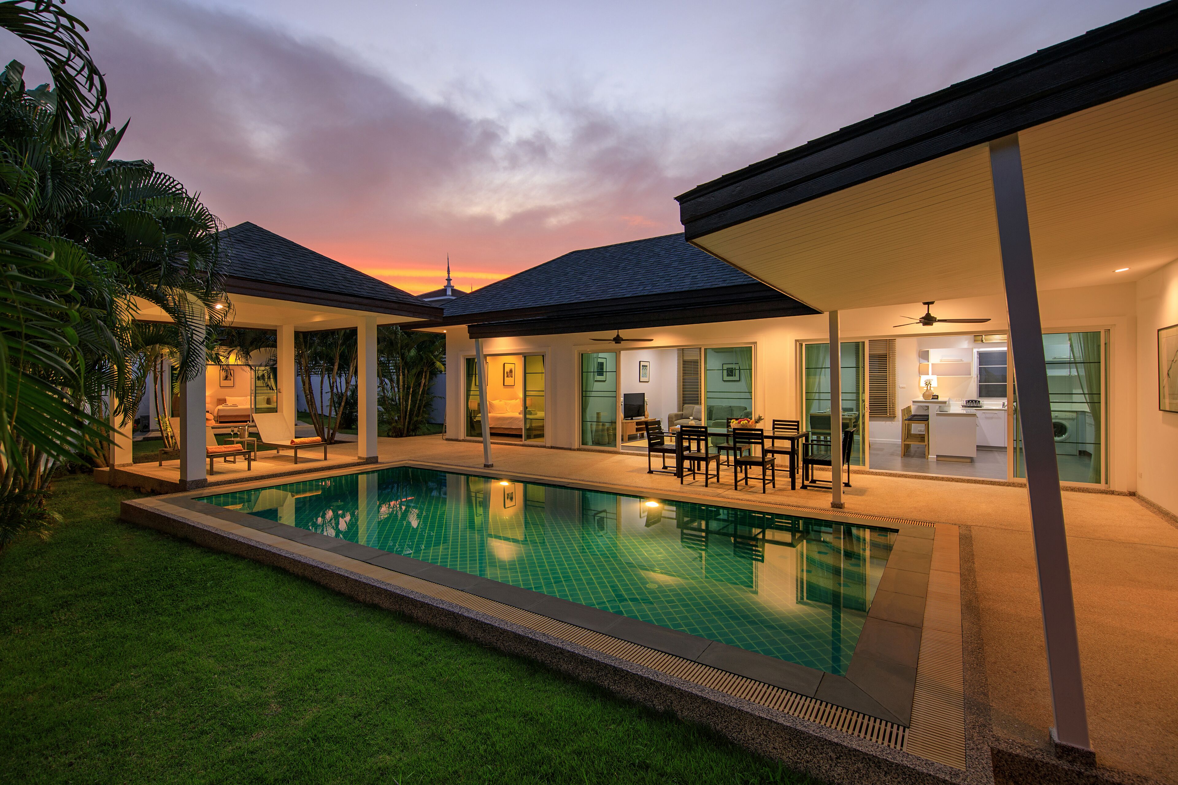 Une maison moderne dotée d’une piscine, d’un patio couvert et d’une pelouse bien entretenue.