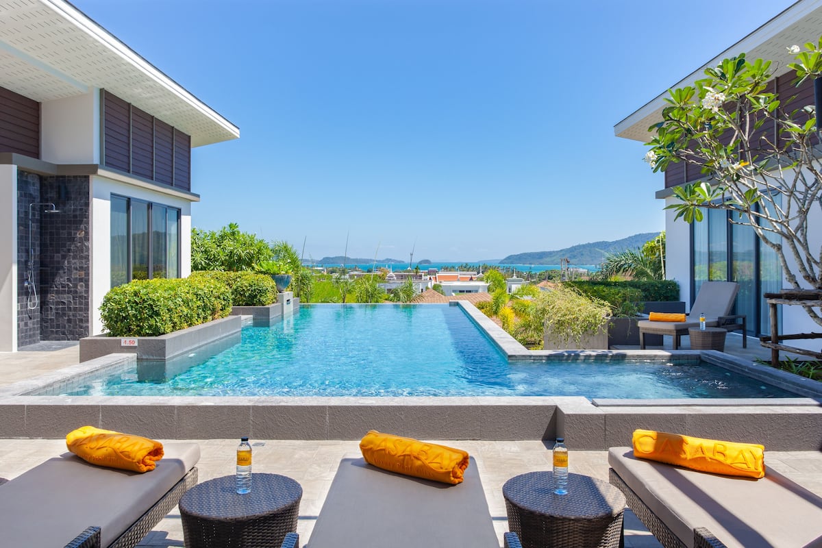 A modern pool area with lounge chairs and a view of the sea.