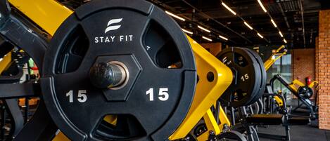 A gym with weightlifting equipment, including barbells marked with '15'.