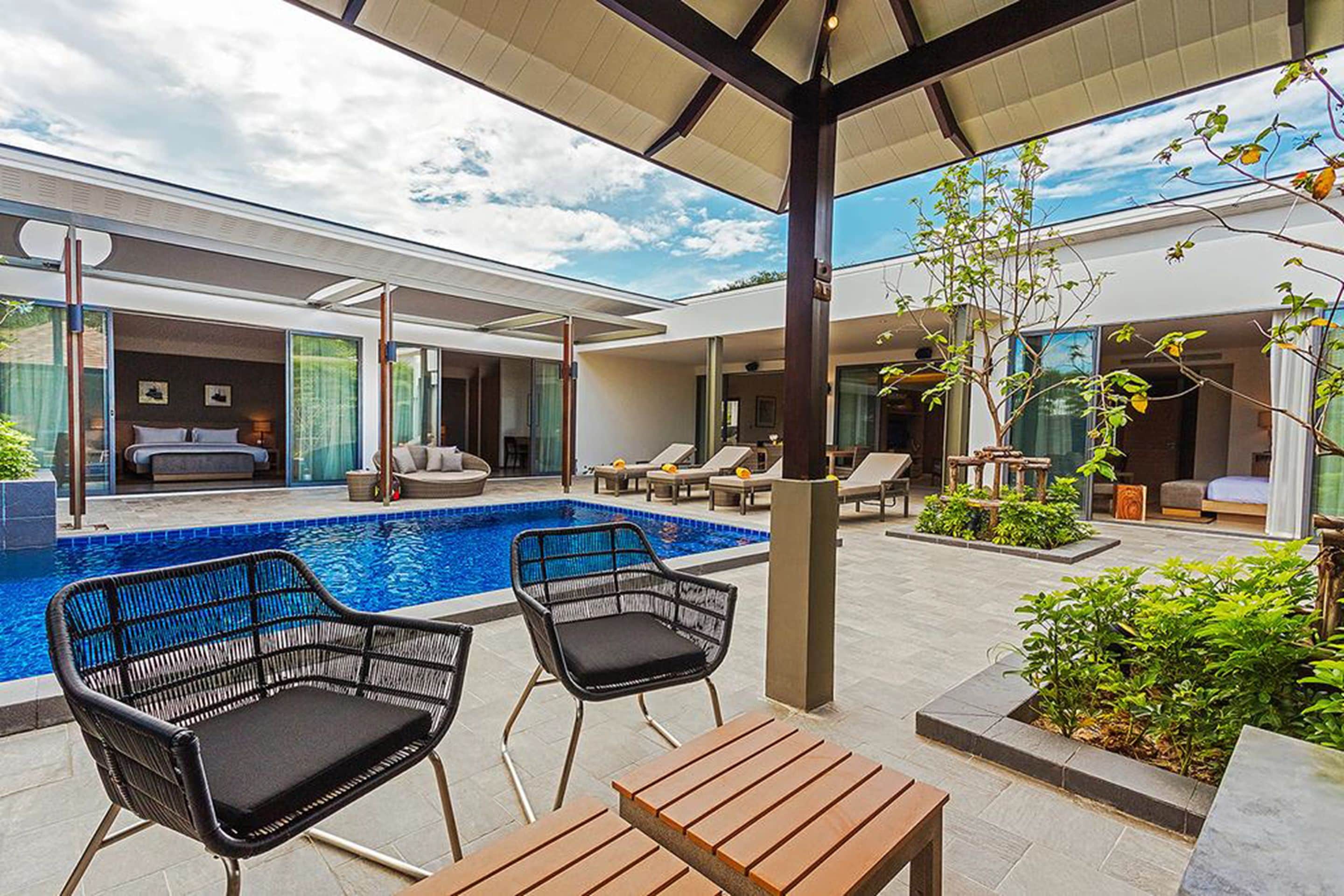 A modern outdoor pool area with lounge chairs and a wooden table.