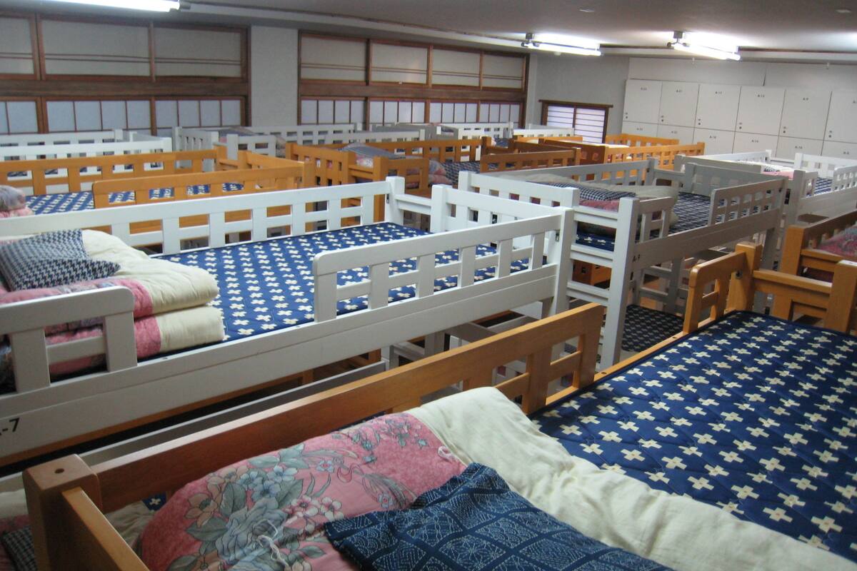 Ein Schlafsaalzimmer mit Etagenbetten, Holz-Kopfteilen und einer gemusterten Bettdecke.