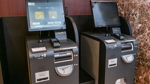 Dos quioscos de autoservicio con lectores de tarjetas, ranura para tarjeta de habitación y ranura para monedas.