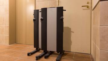 Una màquina d'exercici compacta, penjada a la paret en un racó, amb un paviment de rajoles i una porta beigada al fons.
