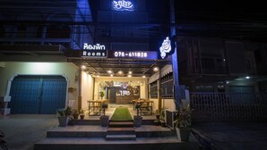 Entrada de hotel con un cartel que dice 'The Sleep Rooms' y un número de contacto.