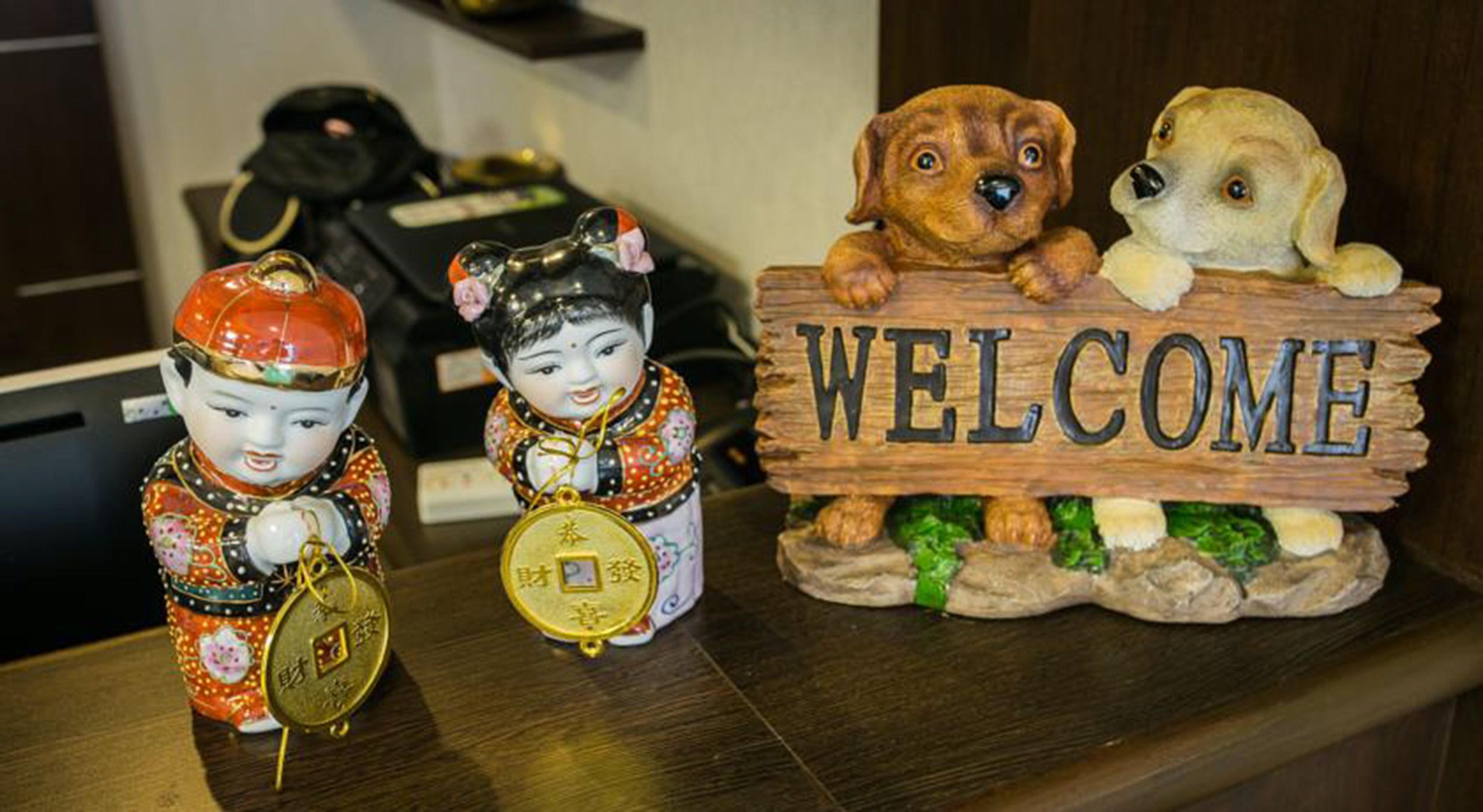 A reception desk with a 'WELCOME' sign, two decorative figurines, and a telephone.