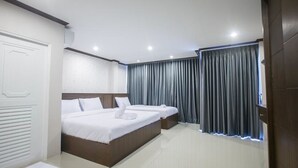 Una habitación de hotel con una cama grande, dos mesitas de noche, un armario y una ventana con cortinas.