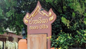 A wooden gate with a sign above it. - Gita's House (Chiang Rai)