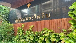 Une enseigne avec des caractères thaïlandais, entourée de verdure.
