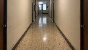 Un long couloir étroit, doté d’un sol carrelé et de murs blancs.