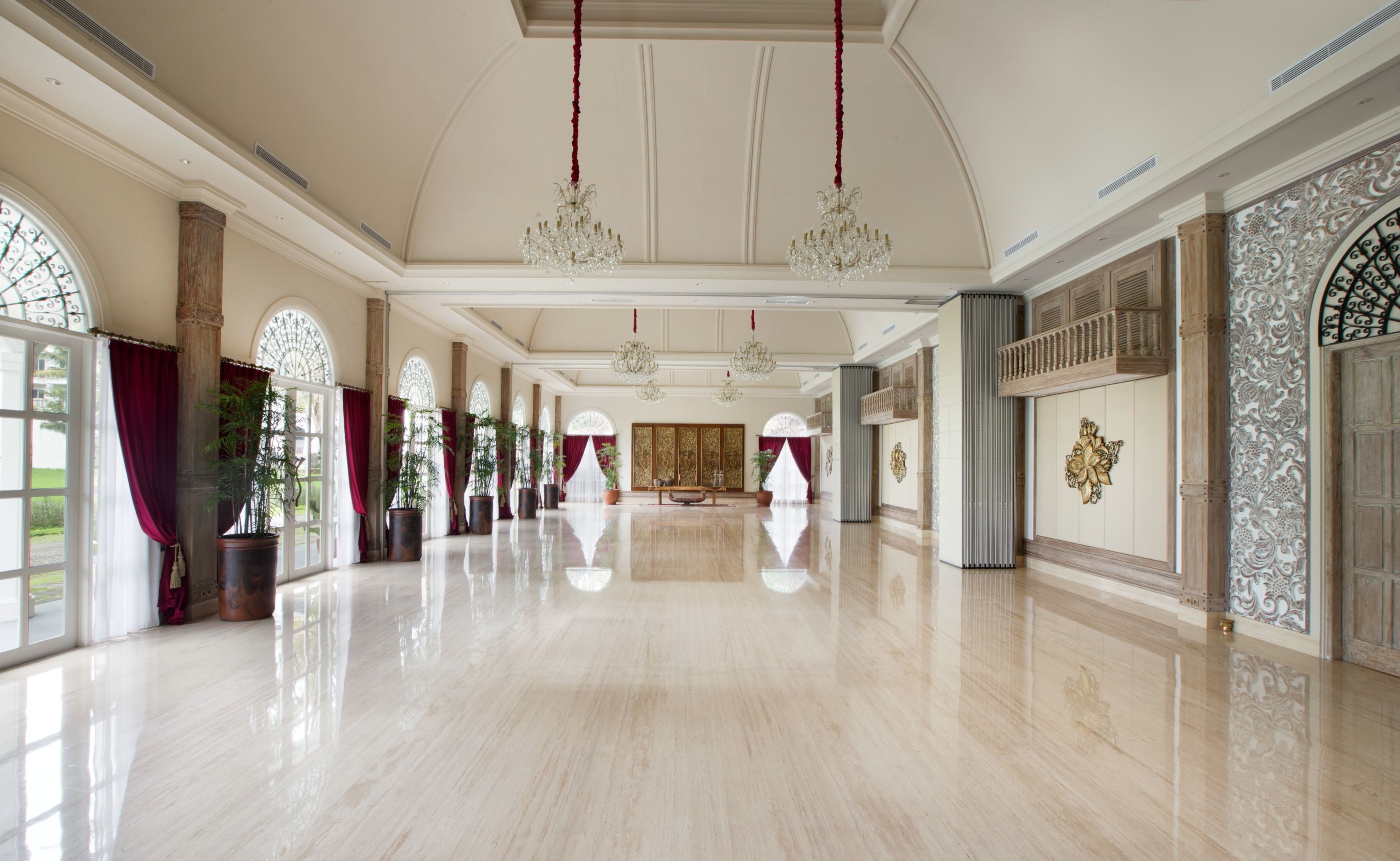 Un vaste hall d’entrée doté de sols en marbre poli, de grandes fenêtres ornées de rideaux rouges et de décorations murales raffinées.