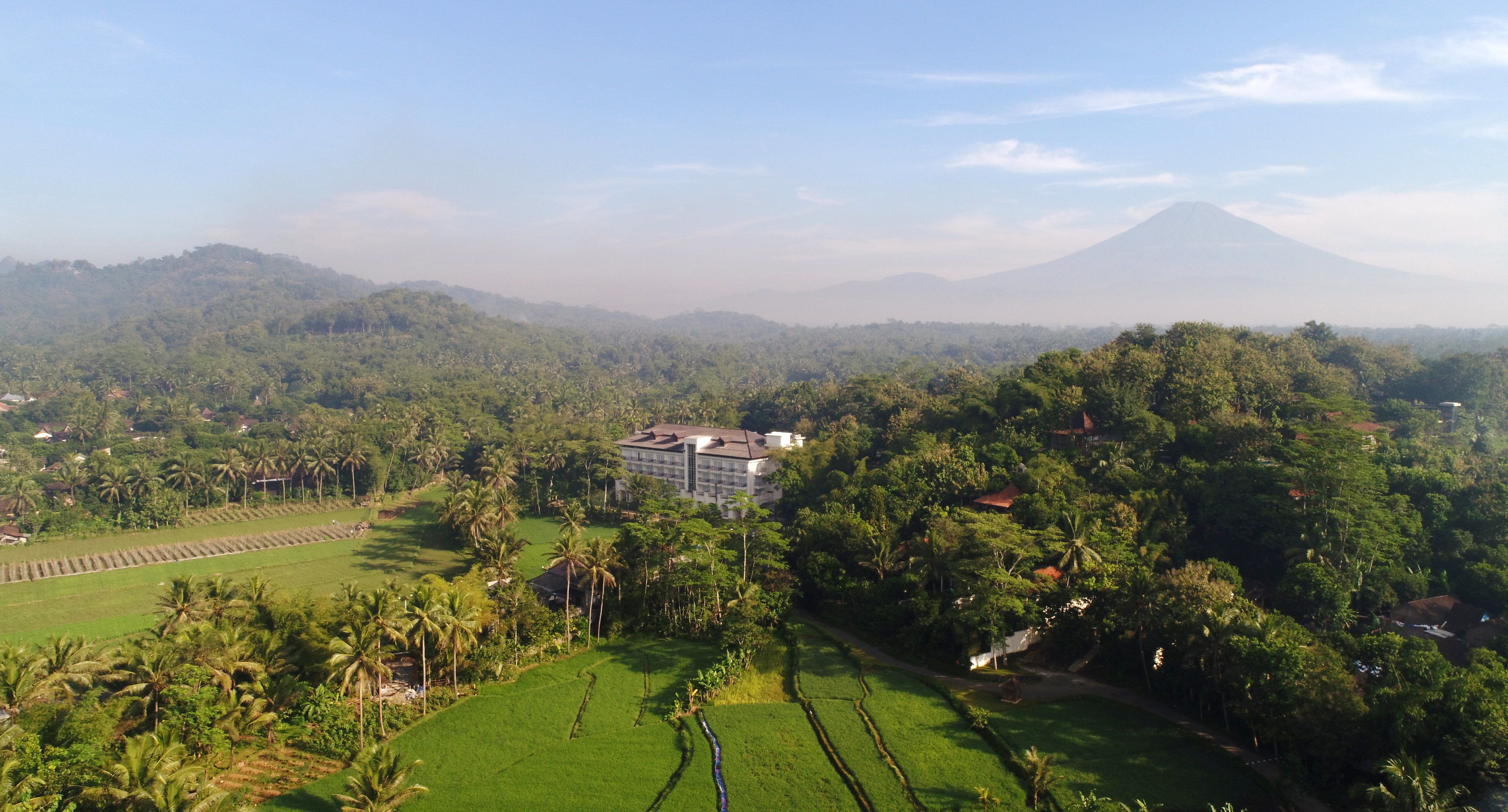 A hotel surrounded by lush greenery and a mountain in the background.