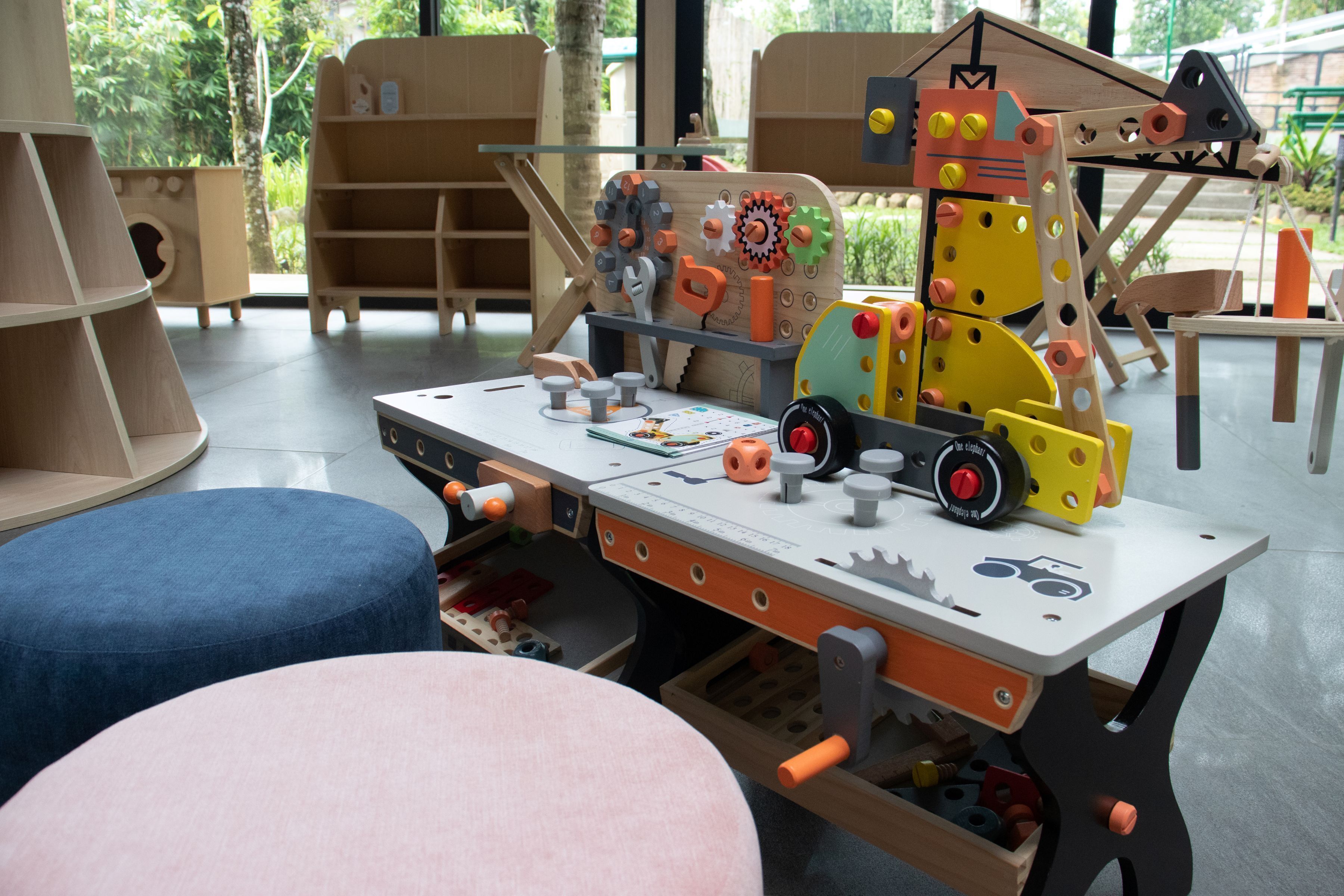 Un área de juegos infantiles con una mesa, taburetes y varios juguetes.