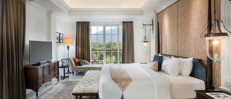 A spacious bedroom with a large bed, a television, a seating area, and a view of the outdoors.