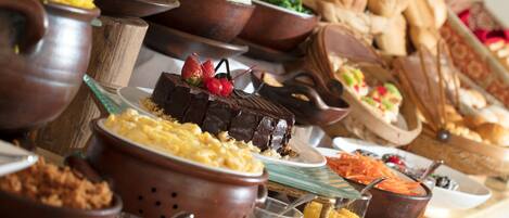 Un bufé con diversos platos, incluyendo un postre de chocolate con fresas, pan y otros alimentos.
