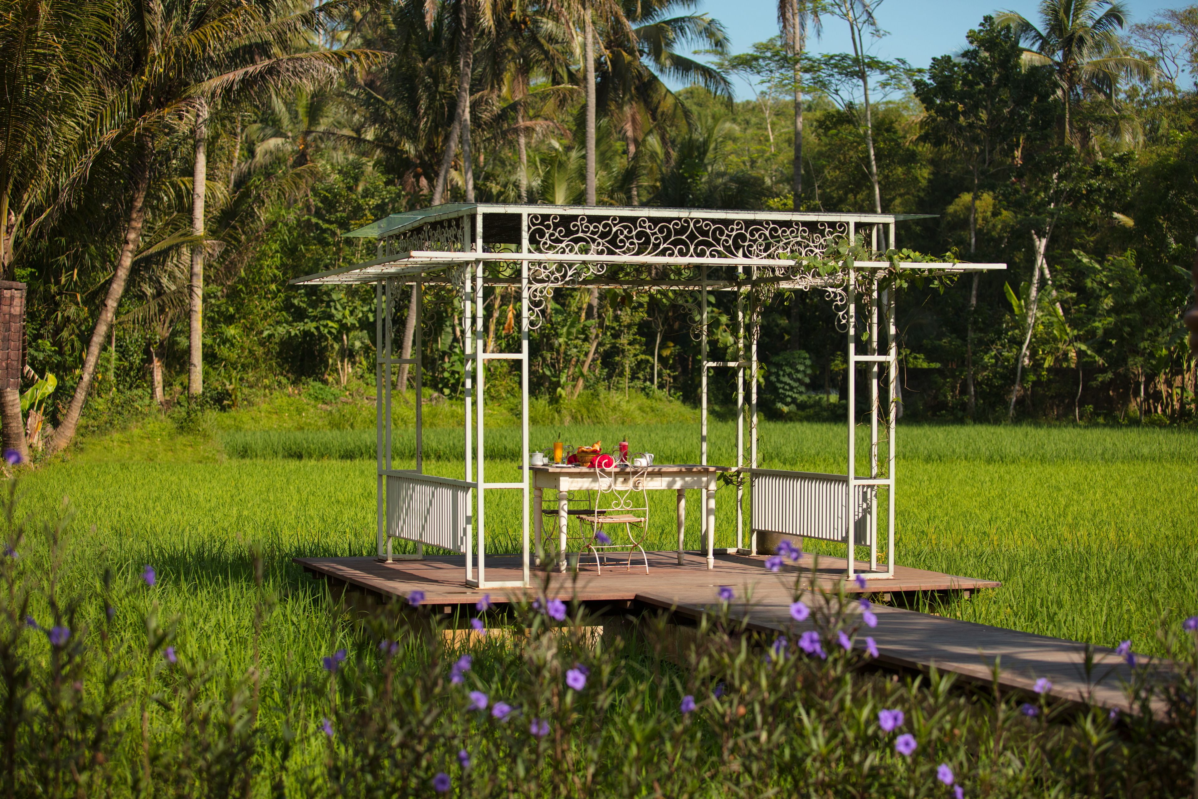 A gazebo with a table and chairs in a lush green field.