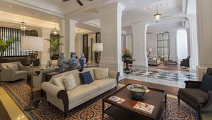 A spacious lobby with a high ceiling, a central seating area with a sofa and armchairs, decorative vases, and a patterned floor. - Plataran Heritage Borobudur Hotel (Borobudur)