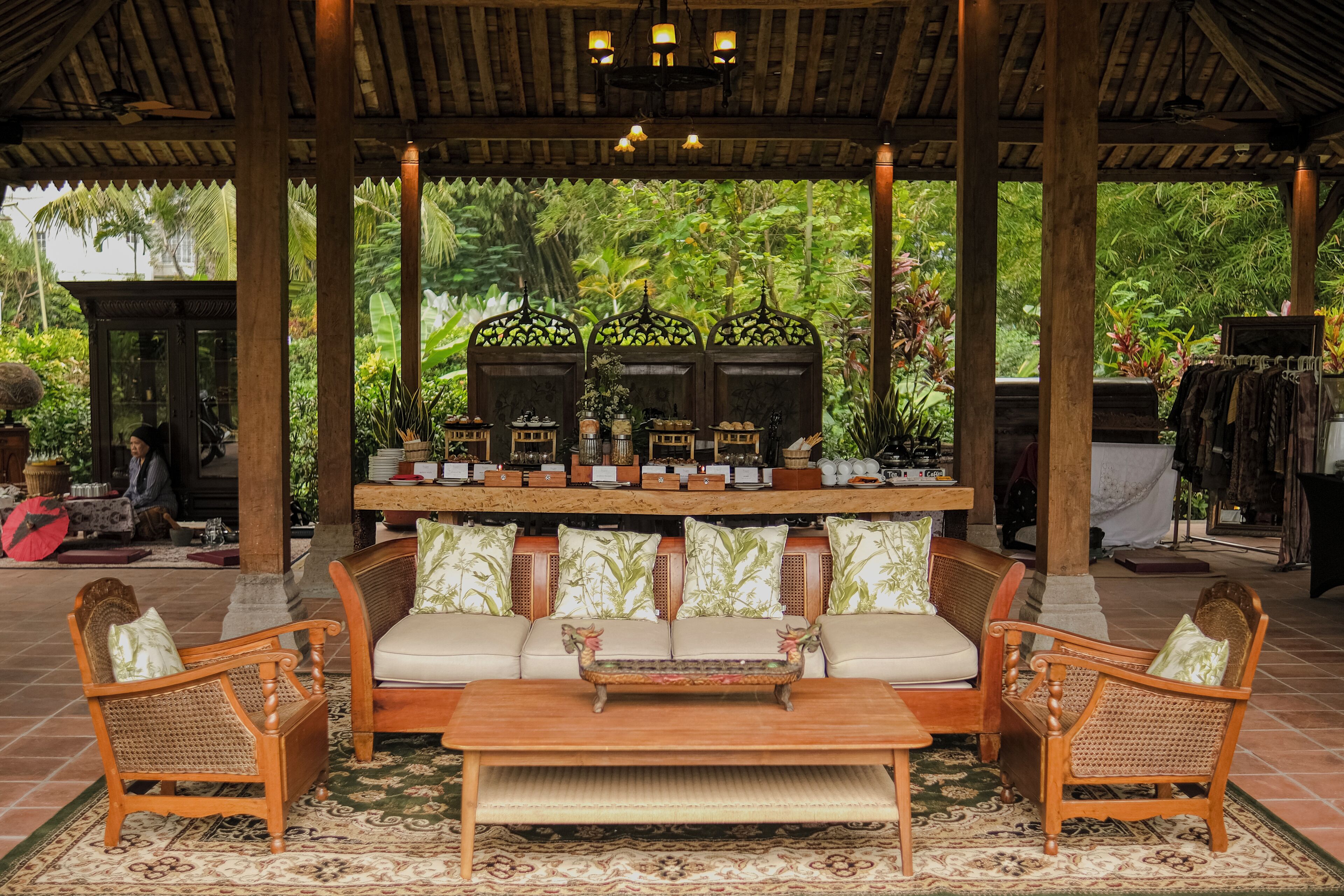 A covered seating area with a sofa, two armchairs, a coffee table, and a decorative bench.