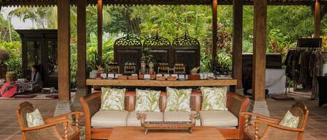 A covered seating area with a sofa, two armchairs, a coffee table, and a decorative bench.