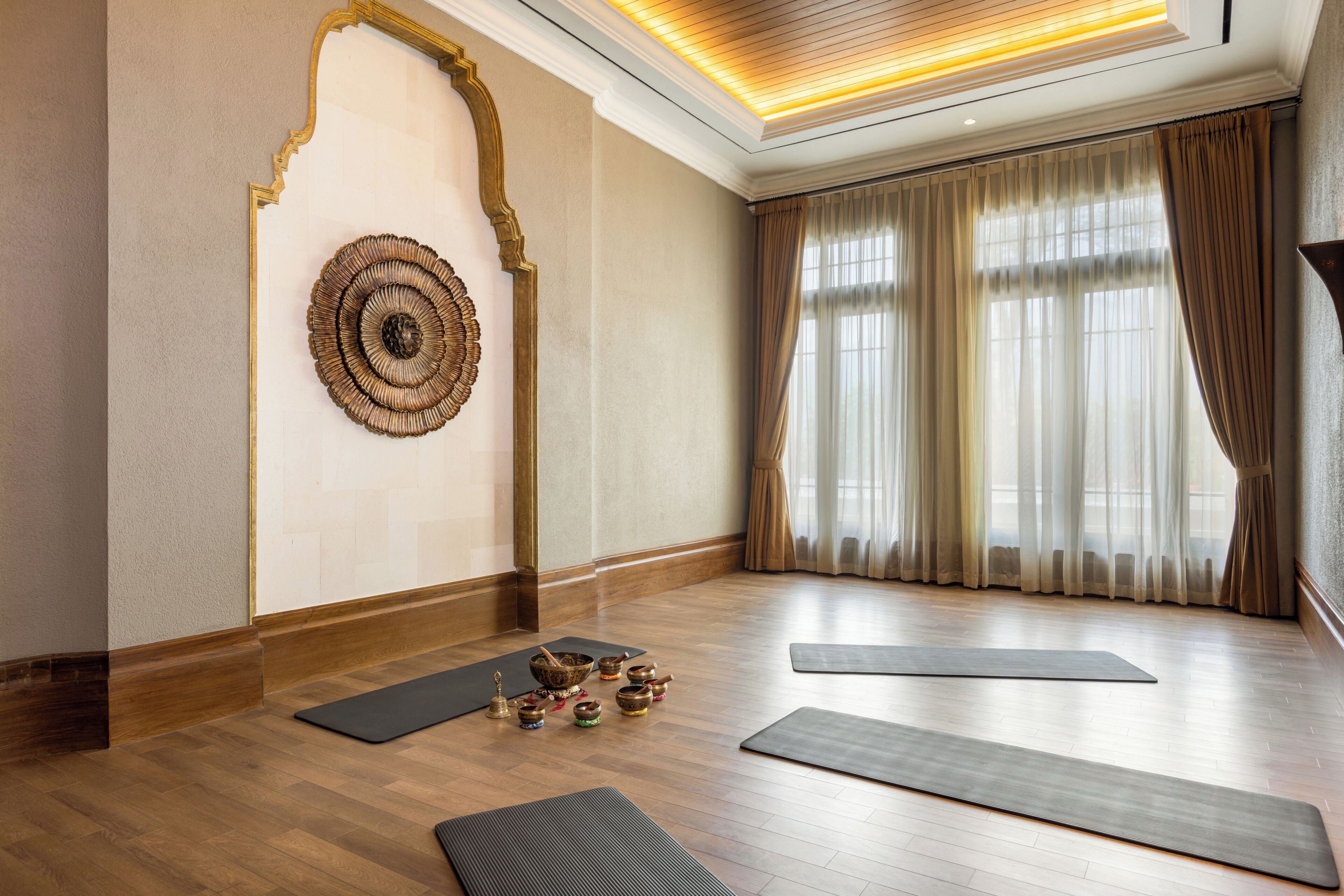 A spacious room with wooden flooring, a large mirror, and exercise mats.