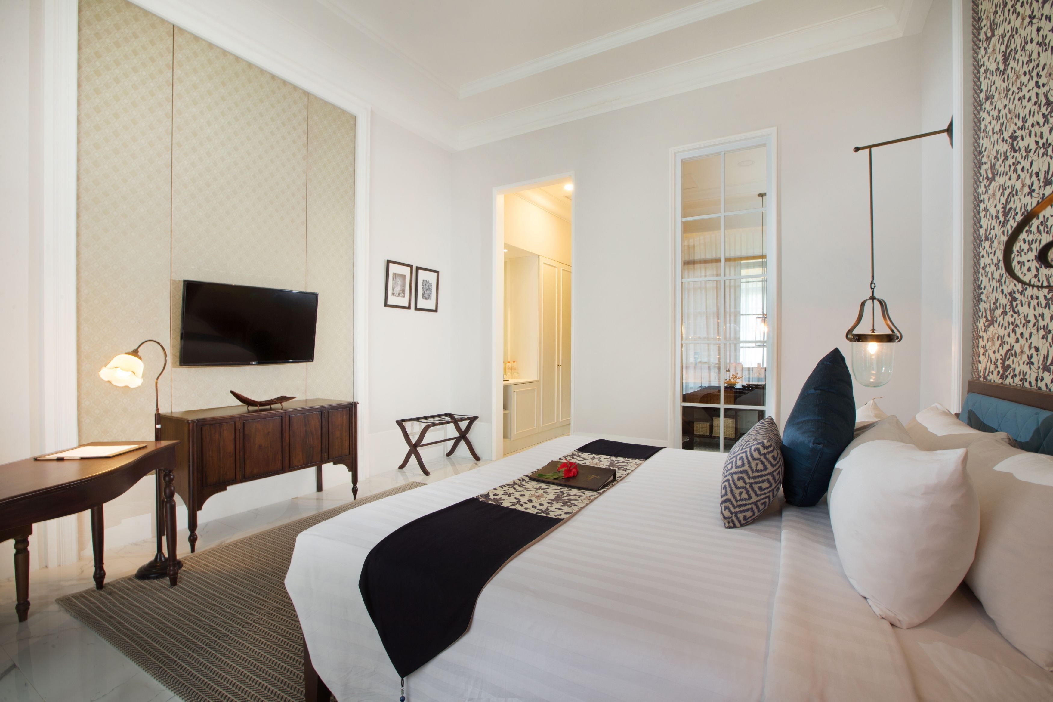 Habitación de hotel con una cama grande, un escritorio con lámpara, televisión y armario.