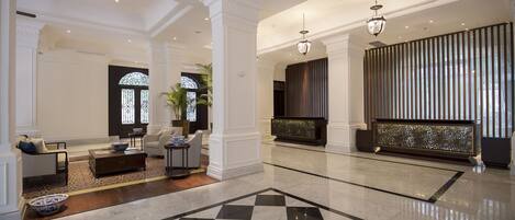 A spacious lobby with a checkered floor, a seating area with sofas and a coffee table, and a large decorative screen.