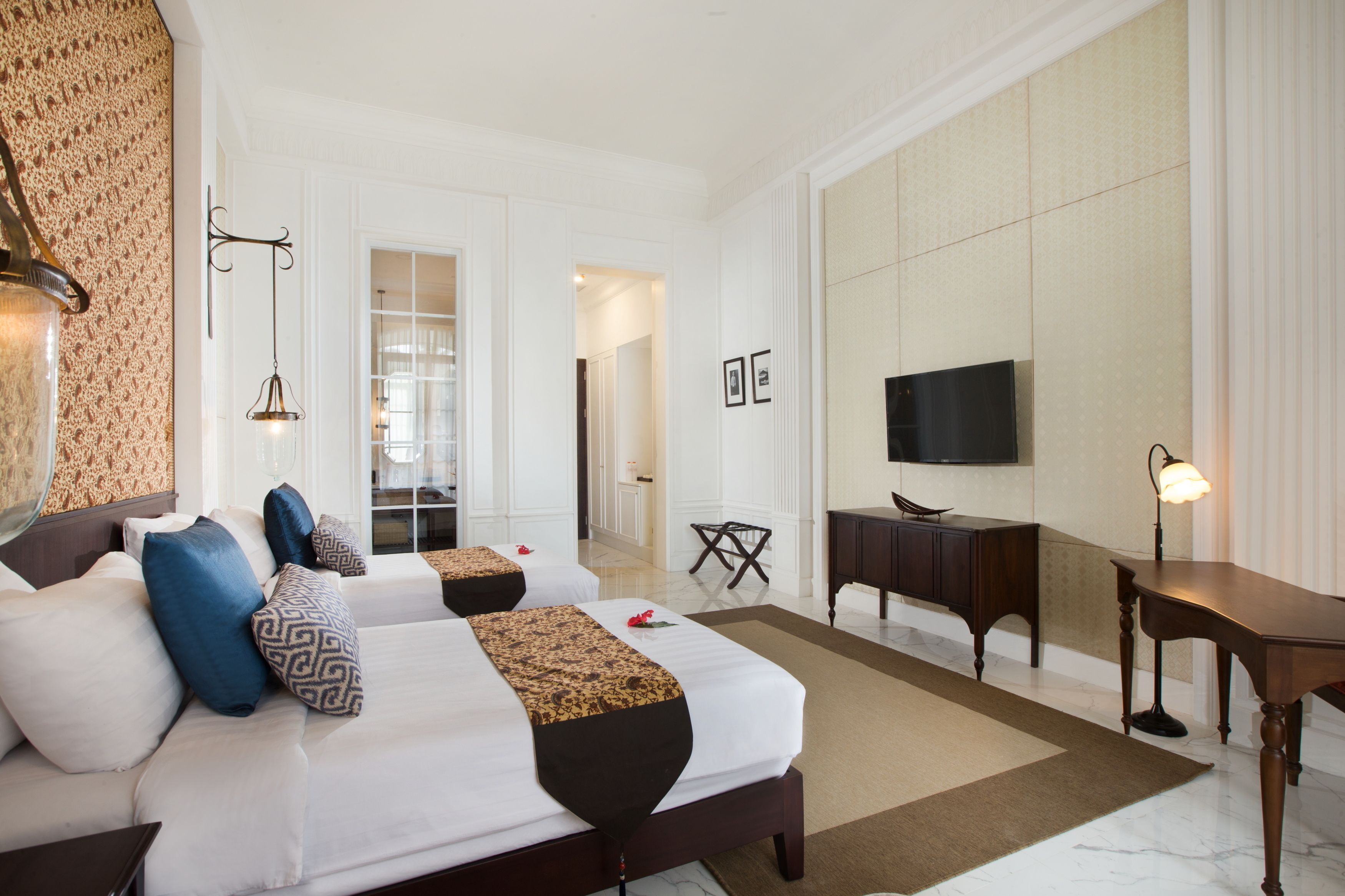 A hotel room with two beds, a TV, a desk, and a chair.