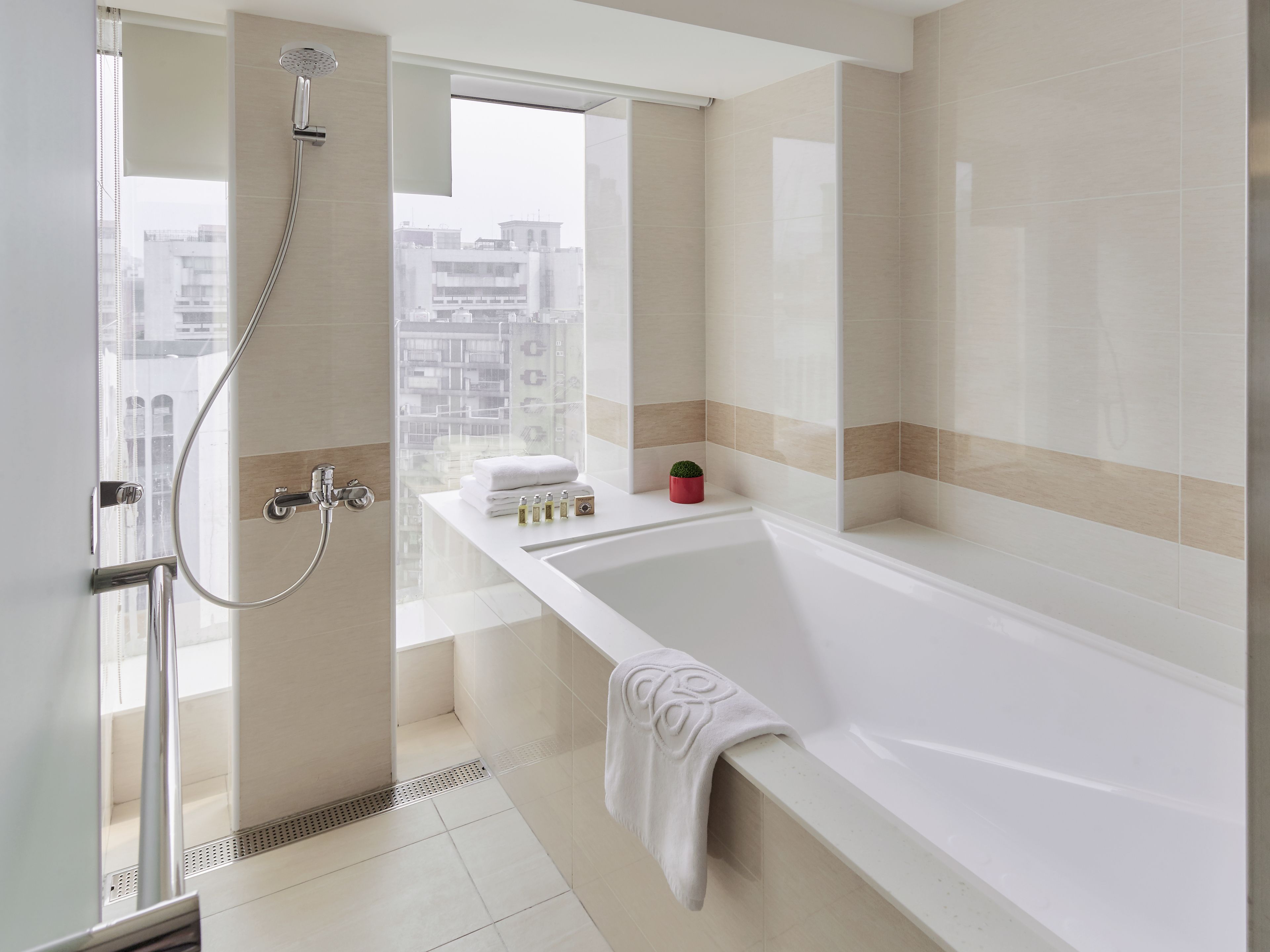 A modern bathroom with a bathtub, shower, and a view of the city.
