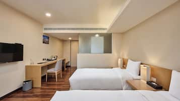 A hotel room with two beds, a desk, a chair, a TV, and a window.