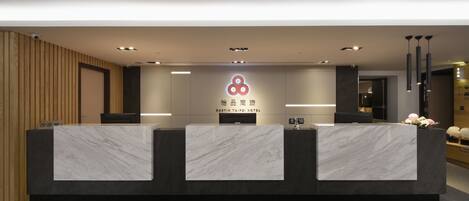 Una recepción de hotel con diseño moderno, que presenta una encimera de mármol y un logotipo en la parte superior.