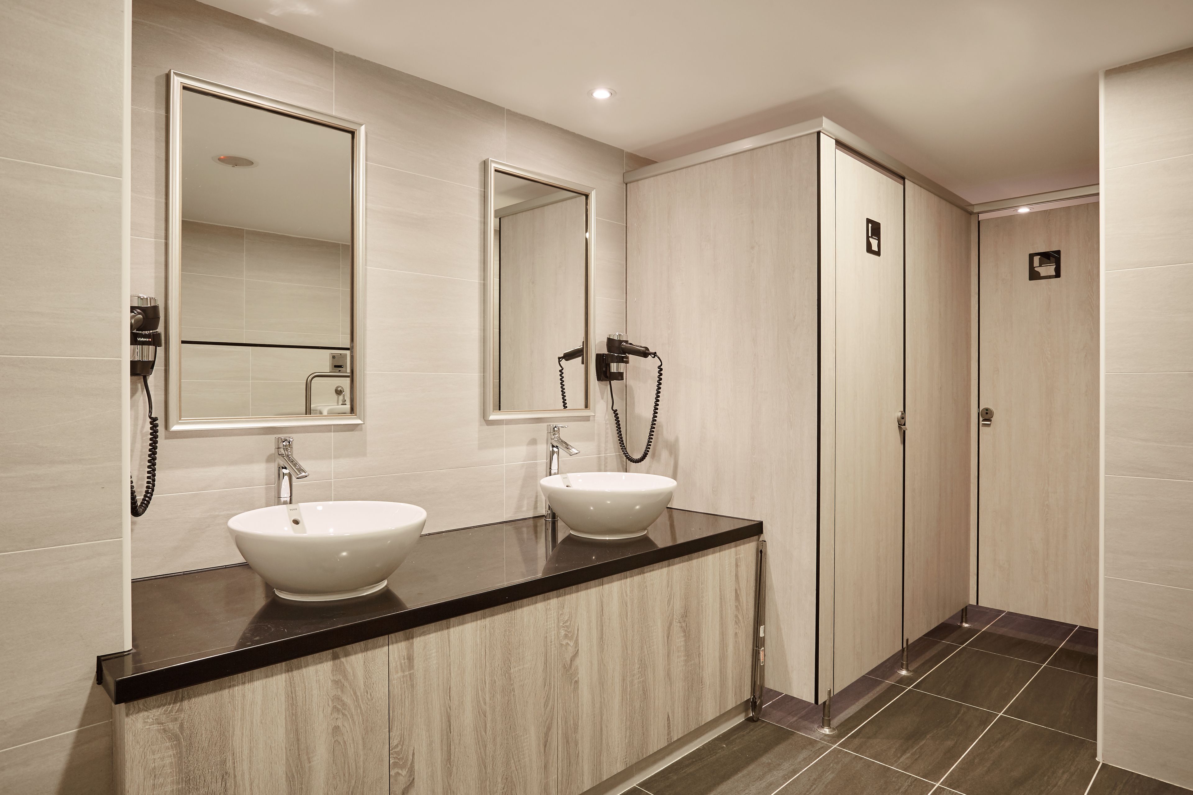A modern bathroom with two sinks, a large mirror, and a walk-in shower.