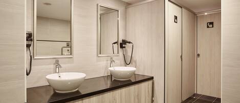 Un baño moderno con dos lavamanos, un espejo grande y una ducha a ras de suelo.