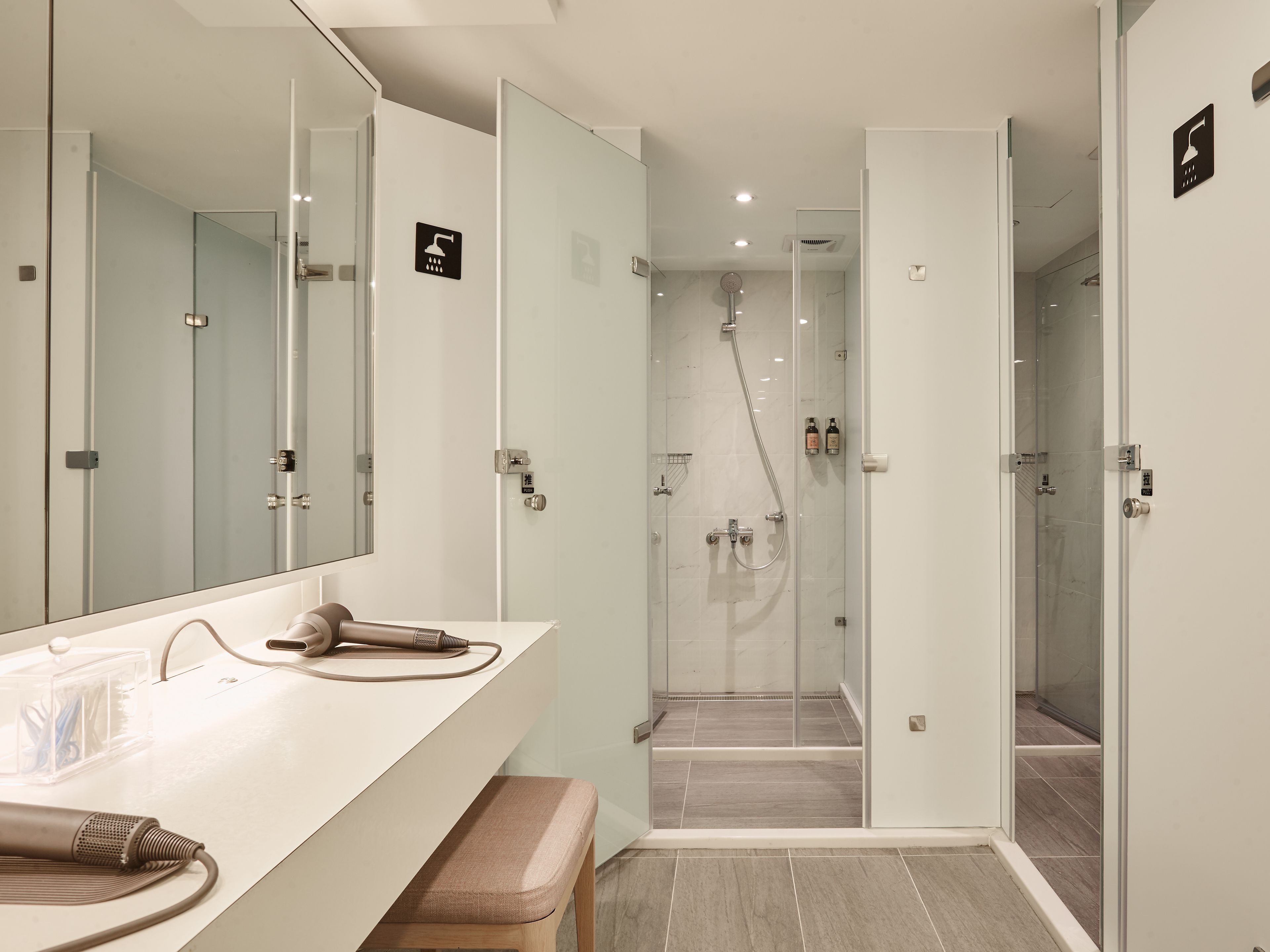 Un baño moderno con un espejo grande, cabina de ducha y tocador con banco.