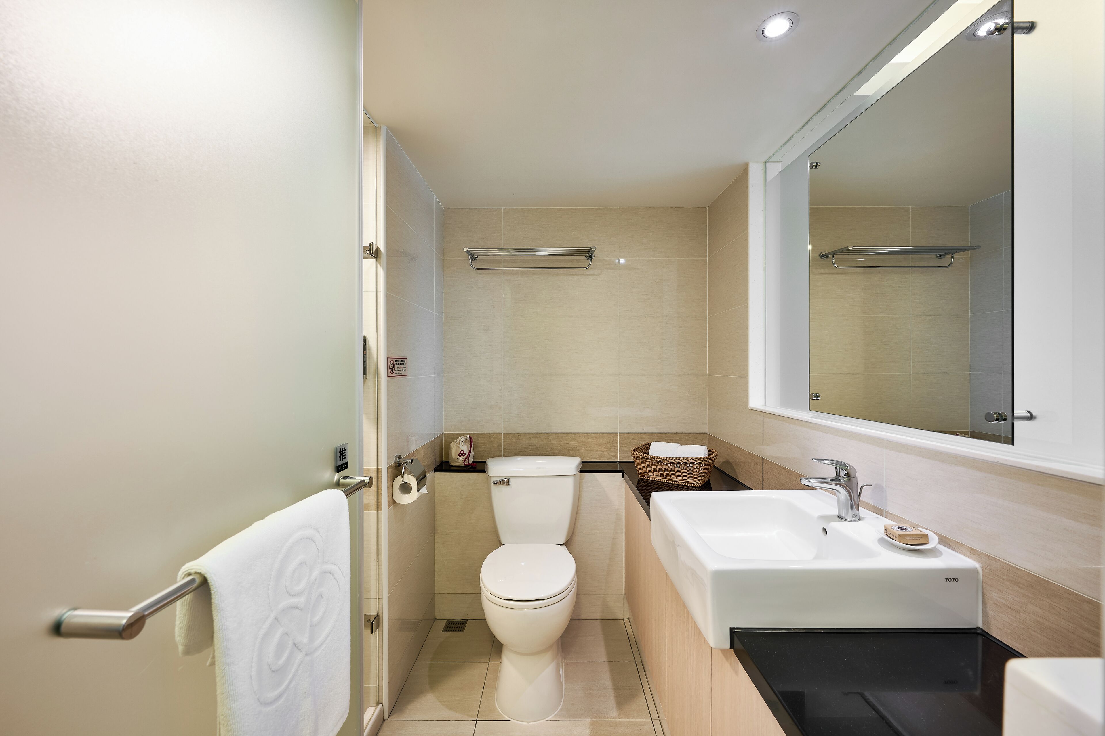 Un baño moderno con inodoro, lavamanos y espejo.