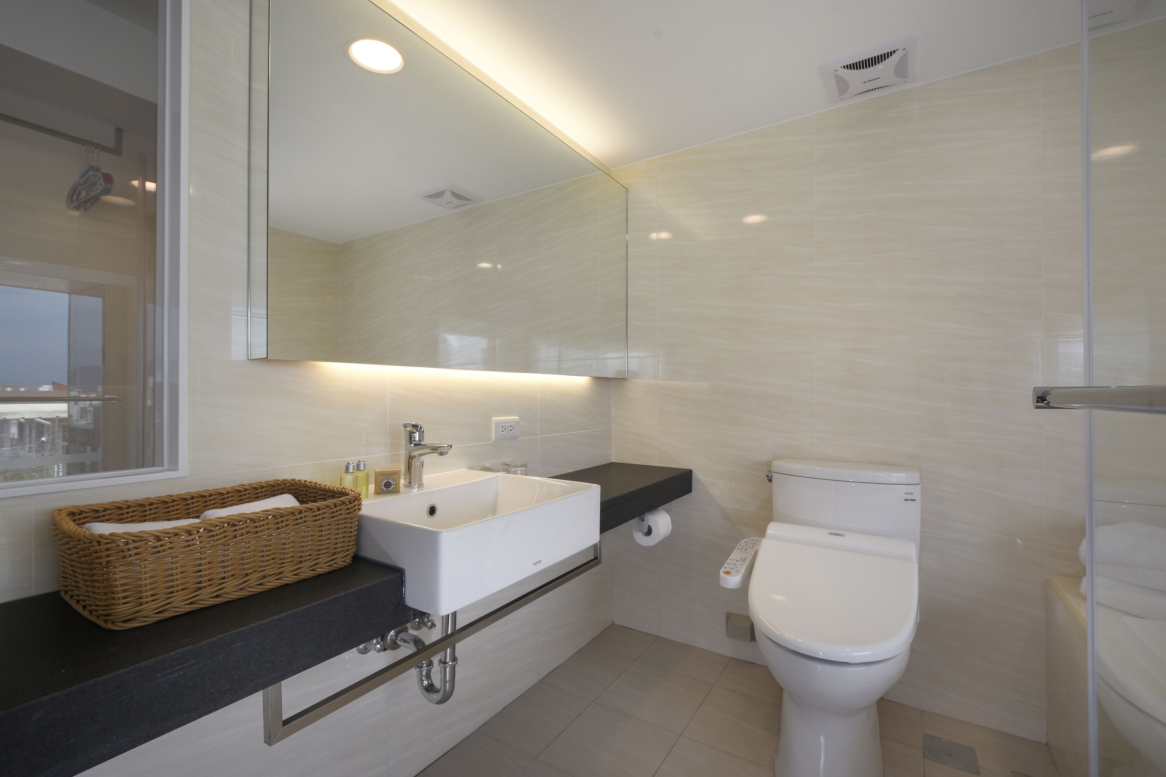 A modern bathroom with a white sink, a toilet, and a large mirror above the sink.