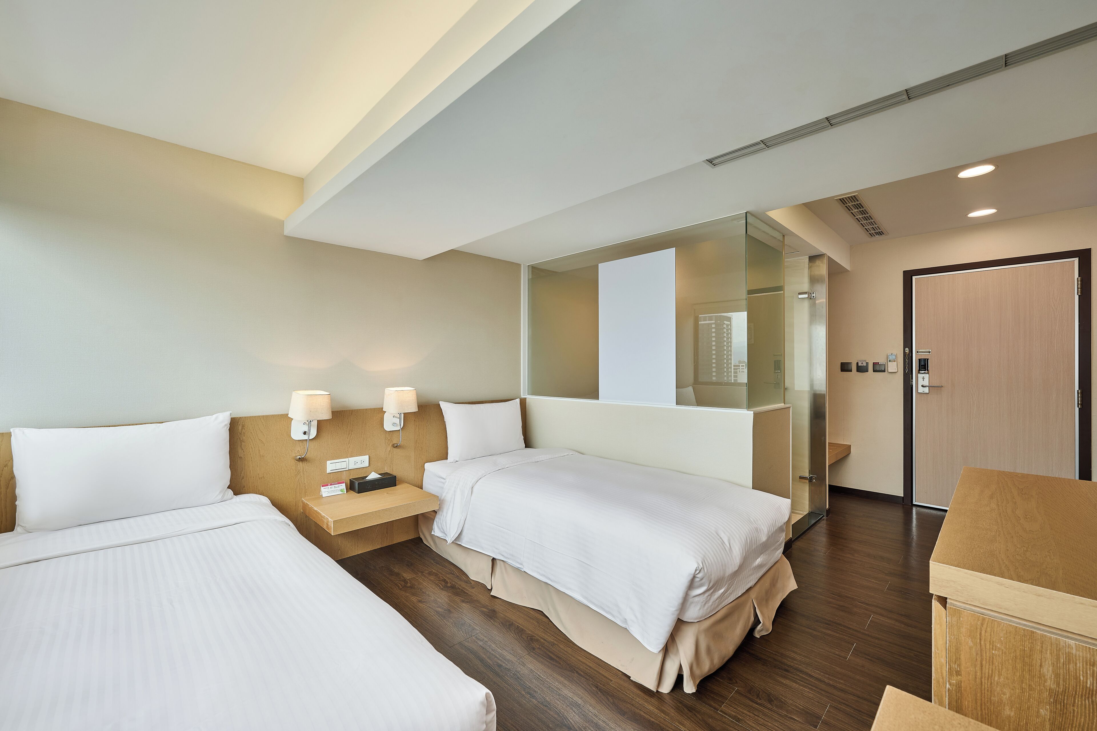 Een hotelkamer met twee bedden, een houten nachtkastje, een spiegel en een kledingkast.