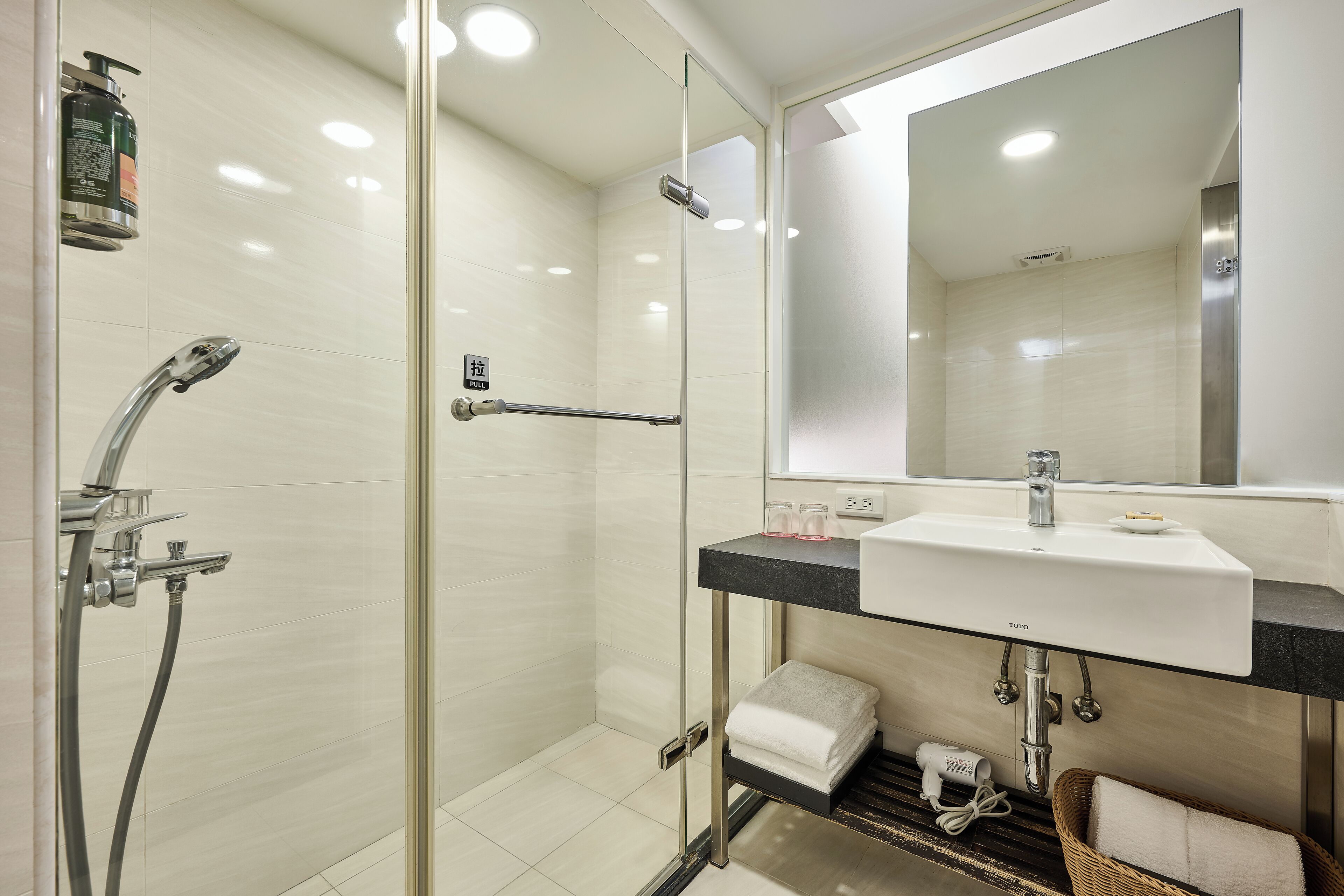 A modern bathroom with a glass-enclosed shower, a sink with a mirror above, and a towel rack.