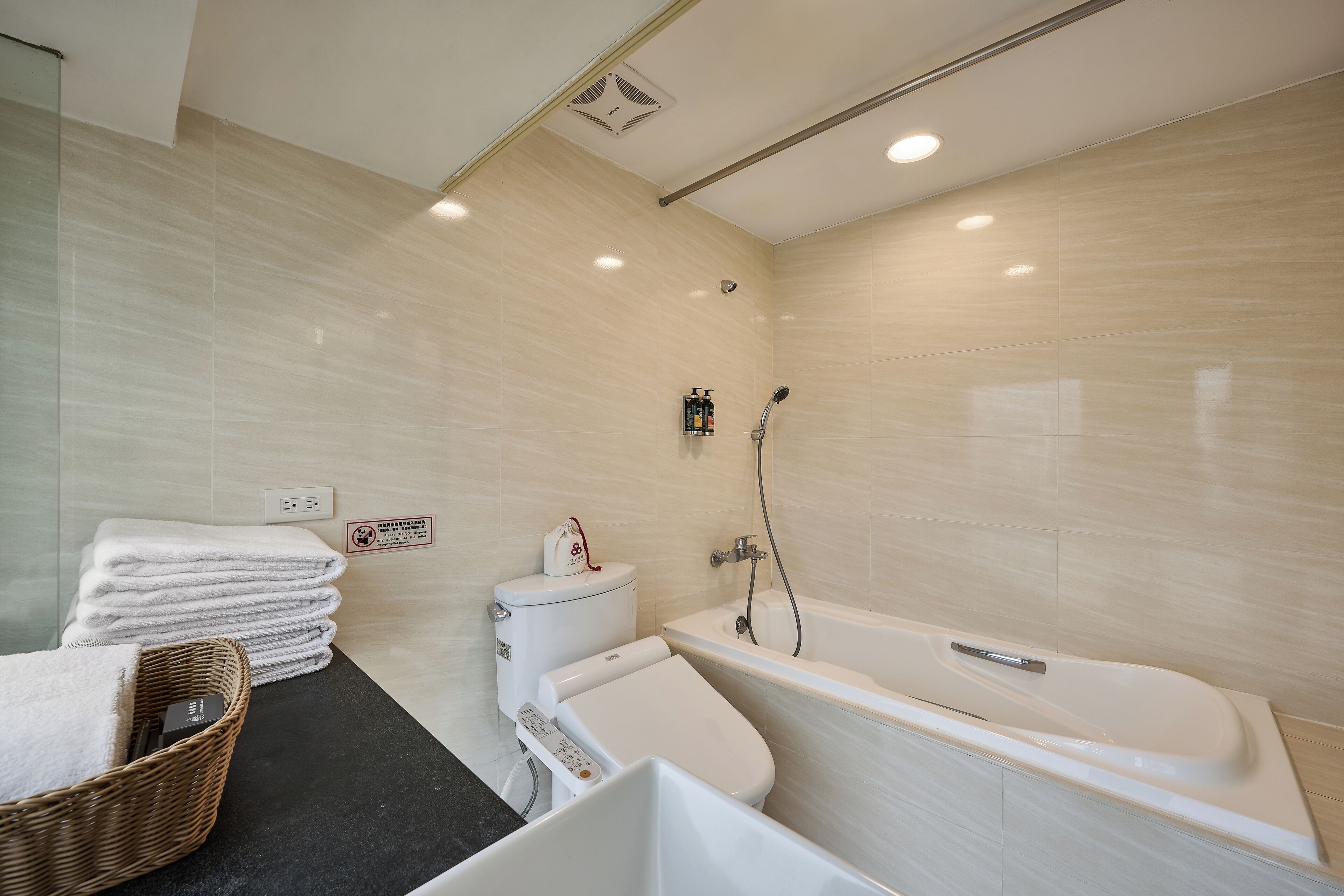 Een moderne badkamer met een badkuip, toilet en een stapel handdoeken.