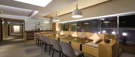 A modern dining area with a long table, multiple chairs, and pendant lighting.