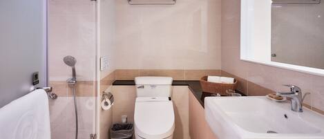 A modern bathroom with a toilet, bidet, shower, and sink.