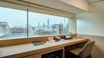 Un espacio de oficina moderno con un amplio ventanal que ofrece vistas a un paisaje urbano, incluyendo una torre destacada.