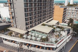 A hotel with multiple balconies, outdoor seating areas, and a pool.
