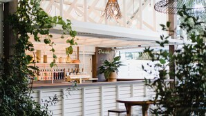 A pool deck area with a bar, potted plants, and a wooden table. - The Island Gold Coast (Surfers Paradise)