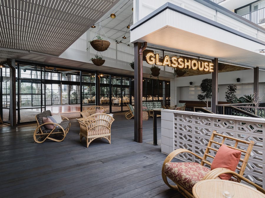 Ein geräumiger Innenbereich mit Korbmöbeln und einem Schild mit der Aufschrift 'GLASSHOUSE'.